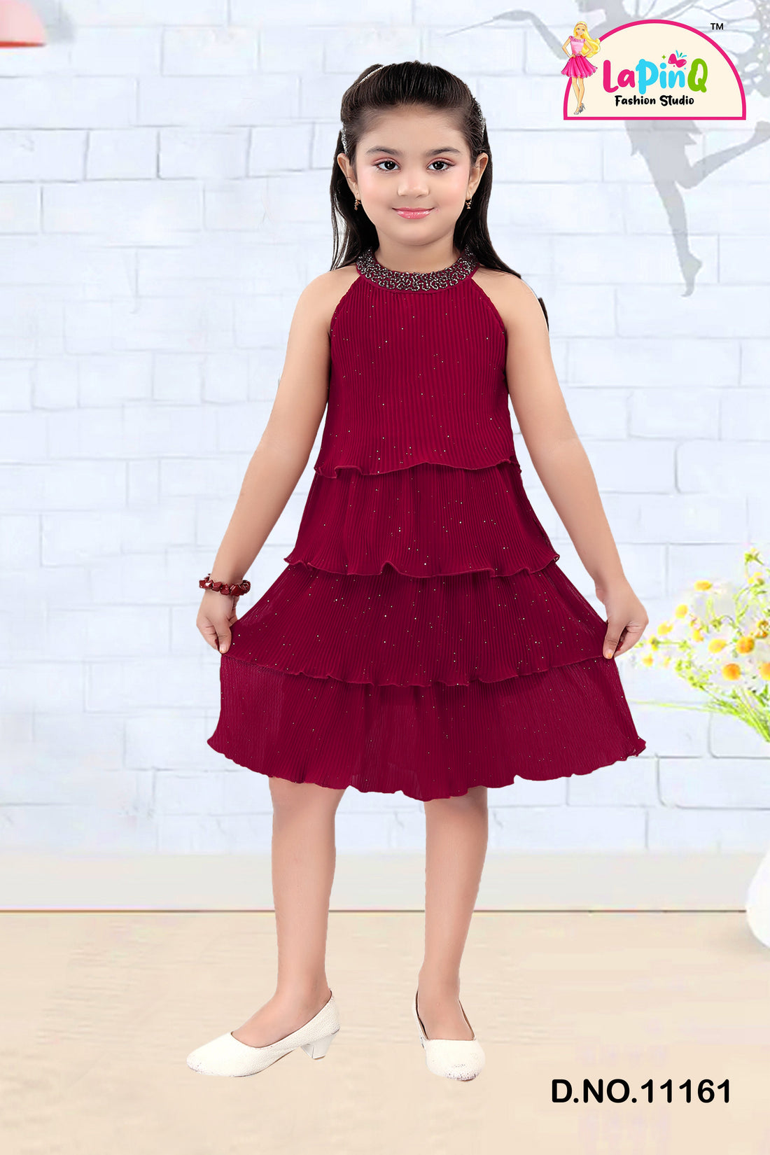 Young girl wearing a black tiered dress with a sparkly neckline in a room.