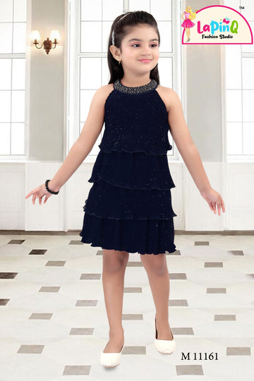 Young girl wearing a black tiered dress with a sparkly neckline in a room.