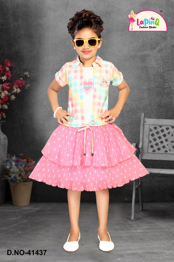 Young girl in a colorful checkered shirt and pink skirt with polka dots, wearing sunglasses, against a gray background.