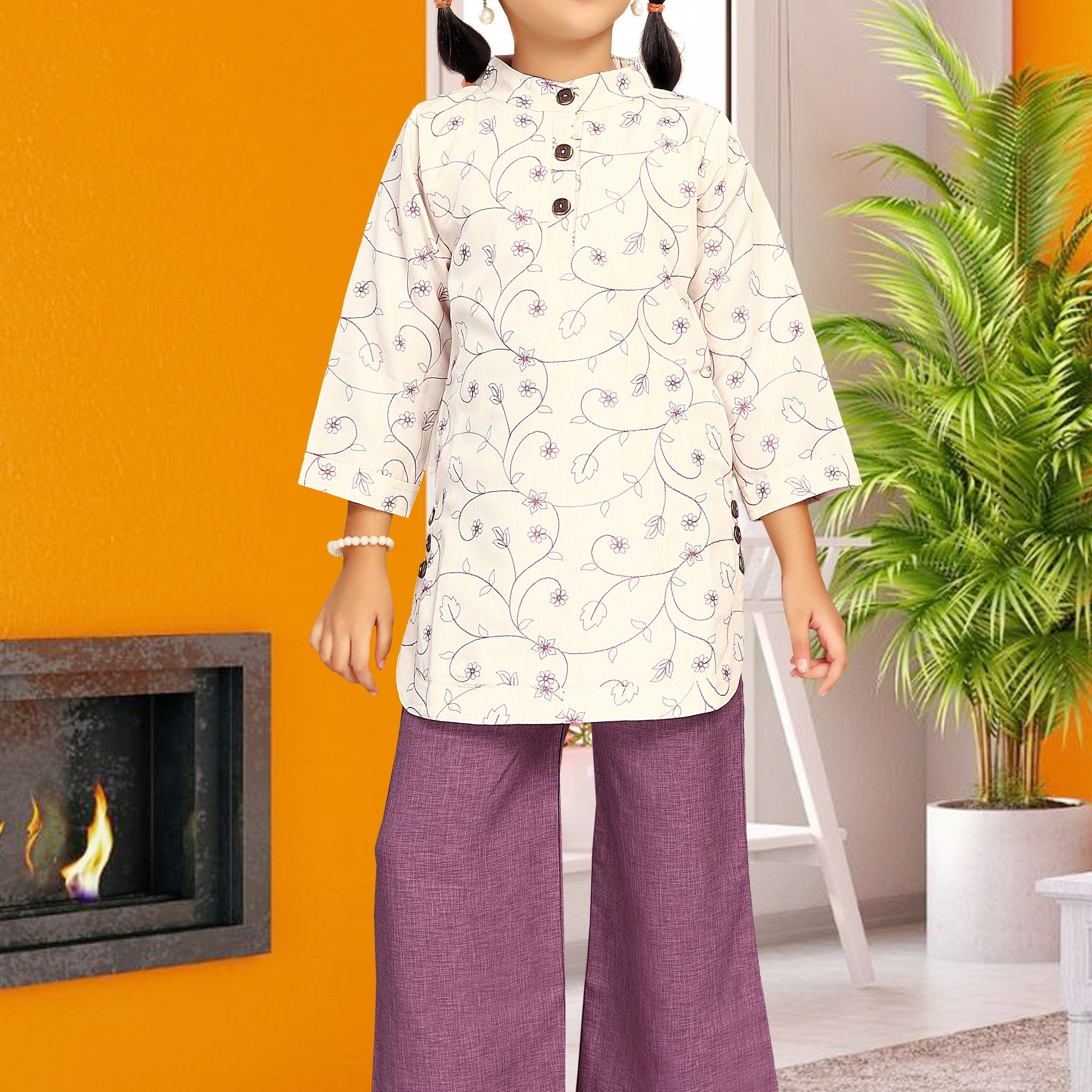 Young girl in a white top and purple pants standing in a room with orange walls and a plant.