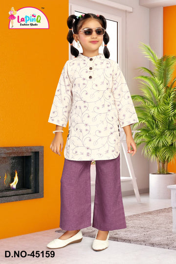 Young girl in a white top and purple pants standing in a room with orange walls and a plant.